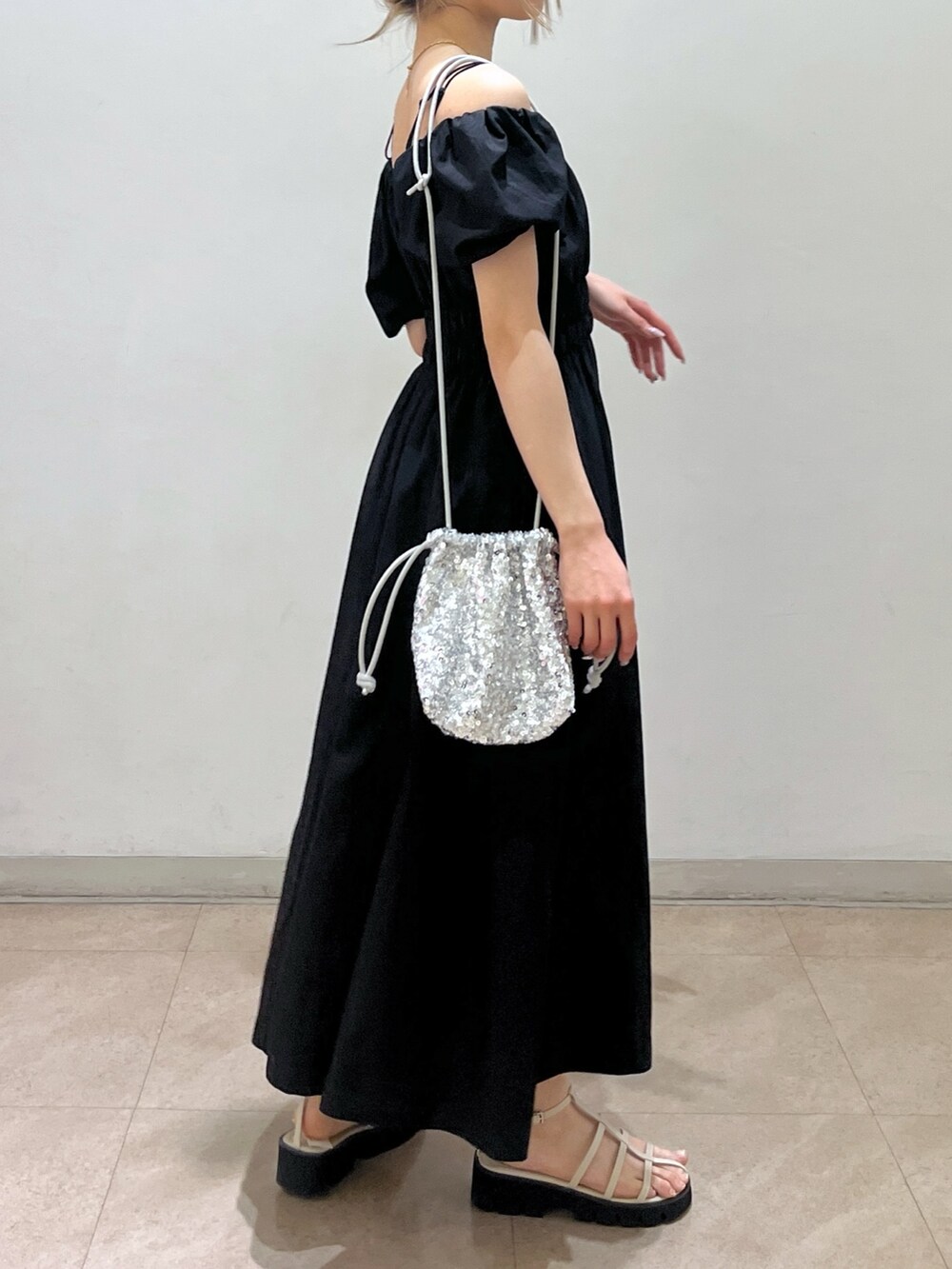 ブラック系のワンピース、シルバー系のハンドバッグ、ホワイト系のサンダルを着用したレディースの春コーディネートの2枚目の写真