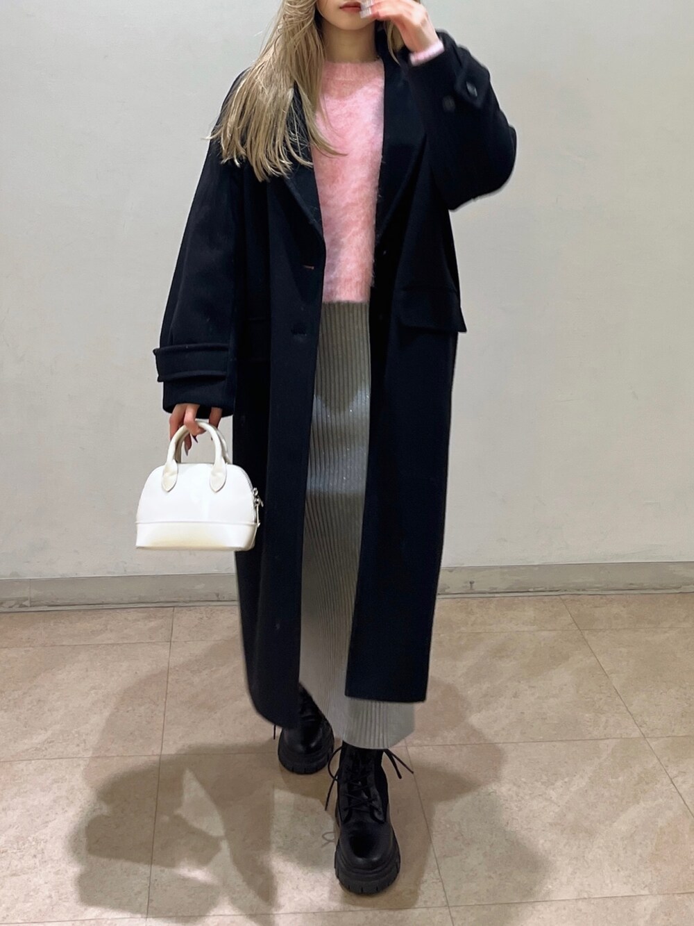 ピンク系のニット/セーター、ブラック系のチェスターコート、ブラック系のブーツを着用したレディースの冬コーディネートの6枚目の写真
