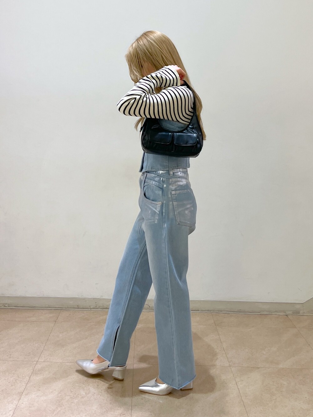 ブルー系のベスト、ホワイト系のニット/セーター、ブラック系のショルダーバッグを着用したレディースの冬コーディネートの4枚目の写真