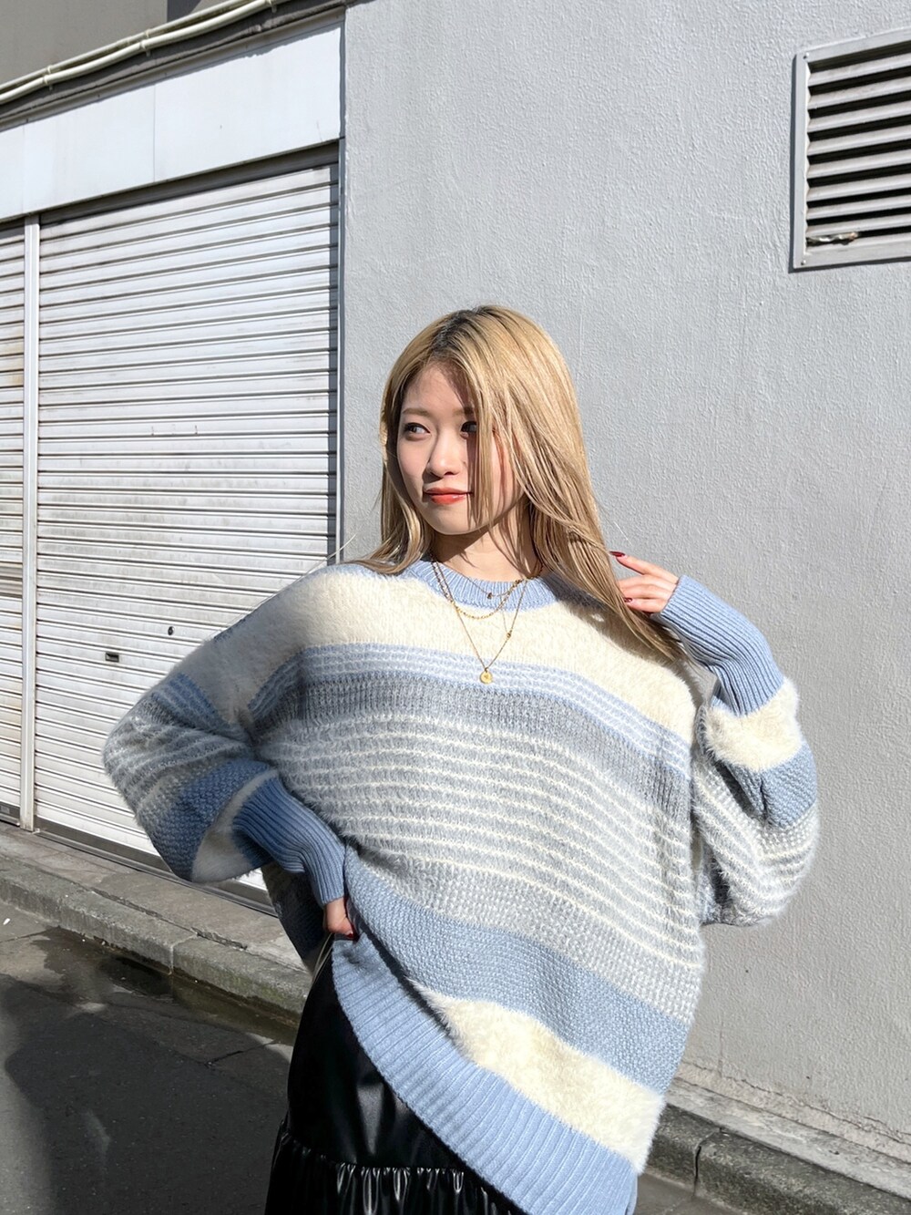 ブルー系のニット/セーター、ブラック系のスカート、ブラック系のブーツを着用したレディースの冬コーディネートの5枚目の写真