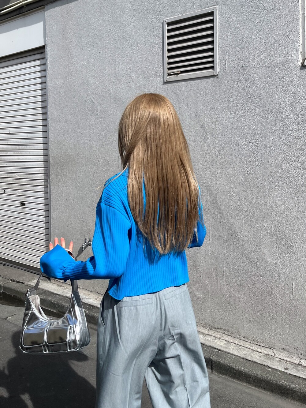 ブルー系のニット/セーター、シルバー系のショルダーバッグ、グレー系のスラックスを着用したレディースの春コーディネートの8枚目の写真