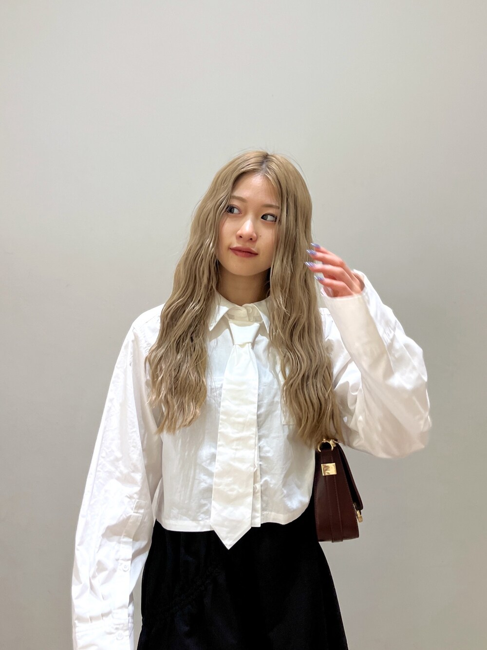 ブラック系のスカート、ホワイト系のシャツ/ブラウス、ブラウン系のショルダーバッグを着用したレディースの春コーディネートの5枚目の写真