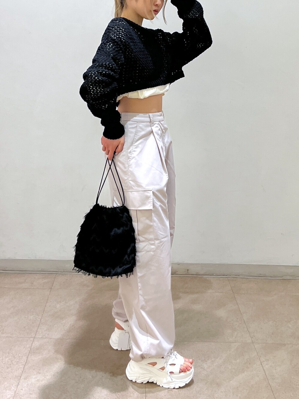 ベージュ系のカーゴパンツ、ブラック系のニット/セーター、ブラック系のハンドバッグを着用したレディースの春コーディネートの5枚目の写真