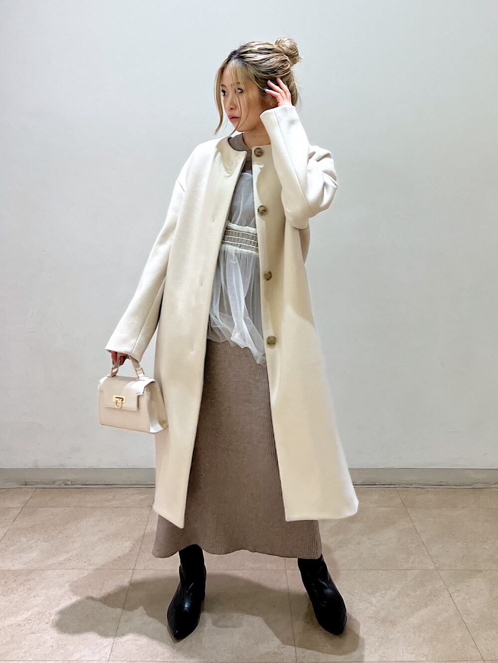 ベージュ系のノーカラーコート、ホワイト系のシャツ/ブラウス、ベージュ系のワンピースを着用したレディースの冬コーディネートの2枚目の写真