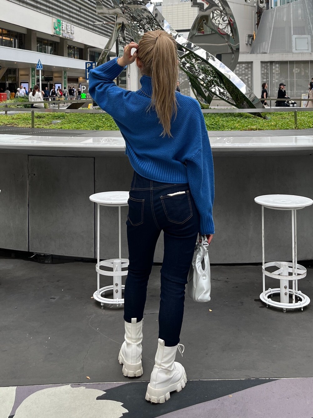 ブルー系のニット/セーター、ブルー系のデニムパンツ、シルバー系のショルダーバッグを着用したレディースの秋コーディネートの4枚目の写真