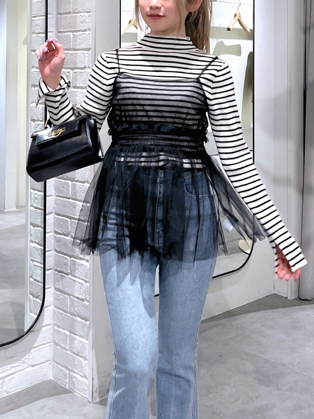 ホワイト系のニット/セーター、ブラック系のシャツ/ブラウス、ブルー系のデニムパンツを着用したレディースの冬コーディネートの6枚目の写真