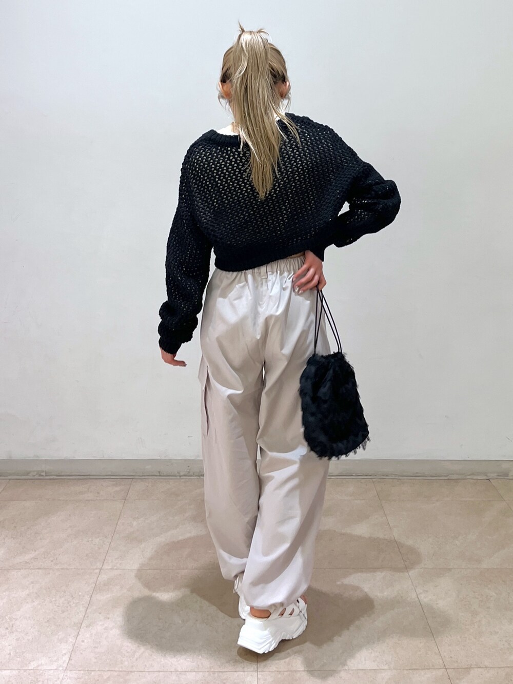 ベージュ系のカーゴパンツ、ブラック系のニット/セーター、ブラック系のハンドバッグを着用したレディースの春コーディネートの2枚目の写真