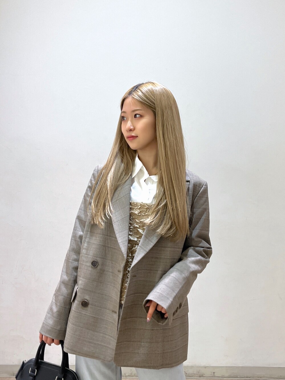 ブラック系のショルダーバッグ、ブルー系のデニムパンツ、ブラック系のパンプスを着用したレディースの春コーディネートの6枚目の写真