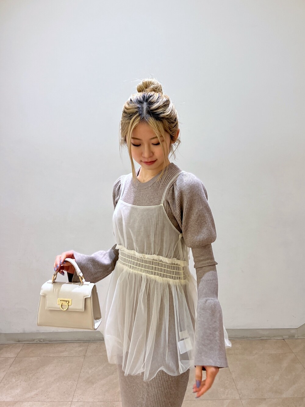 ホワイト系のショルダーバッグ、ブラック系のブーツ、ベージュ系のワンピースを着用したレディースの冬コーディネートの7枚目の写真