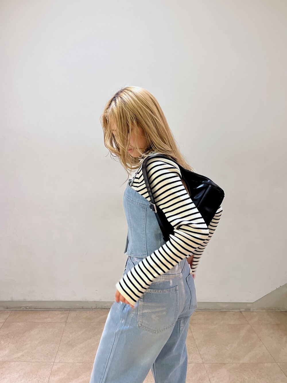 ブルー系のベスト、ホワイト系のニット/セーター、ブラック系のショルダーバッグを着用したレディースの冬コーディネートの7枚目の写真