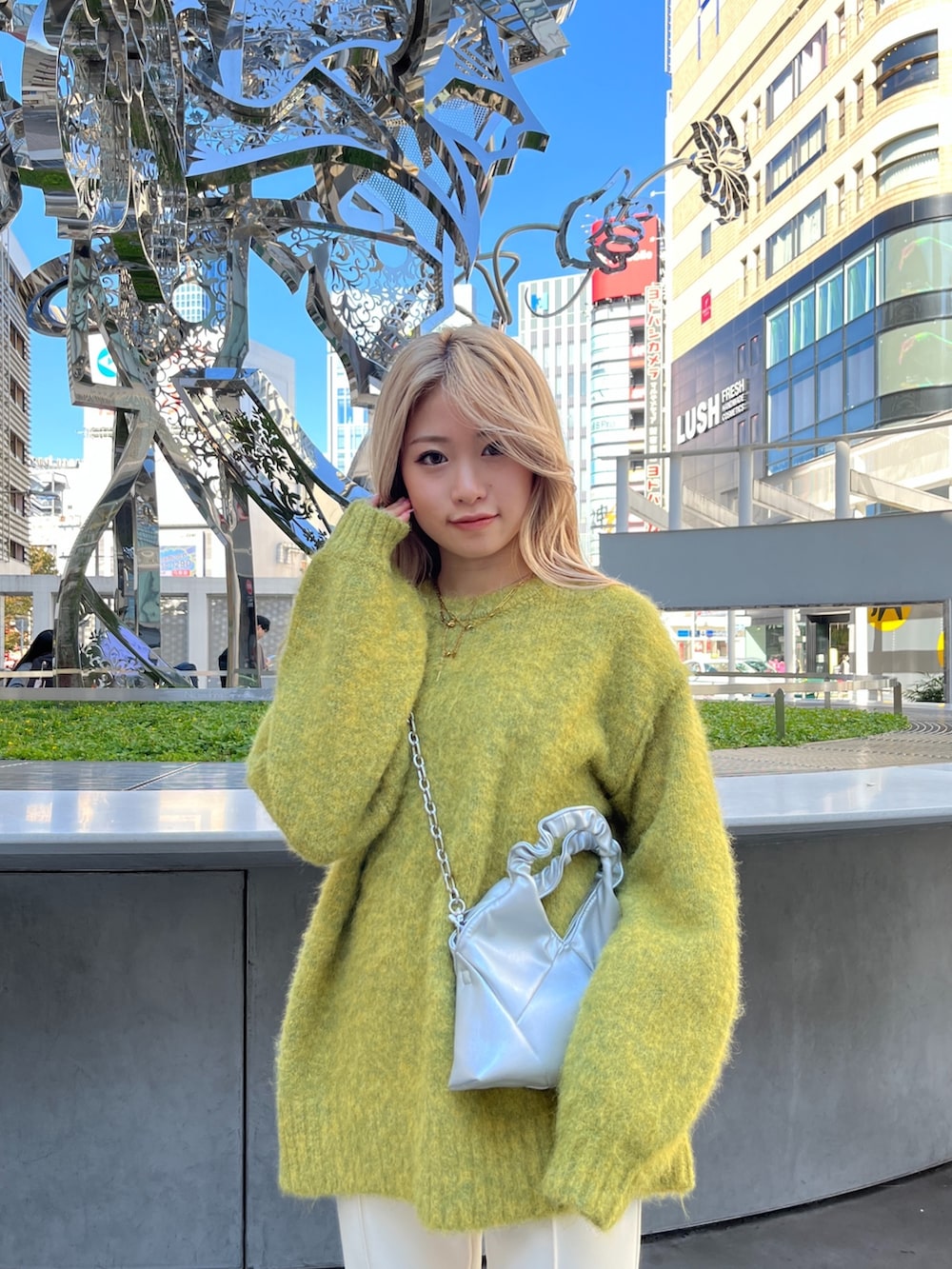 イエロー系のニット/セーター、シルバー系のショルダーバッグ、ホワイト系のスラックスを着用したレディースの秋コーディネートの8枚目の写真