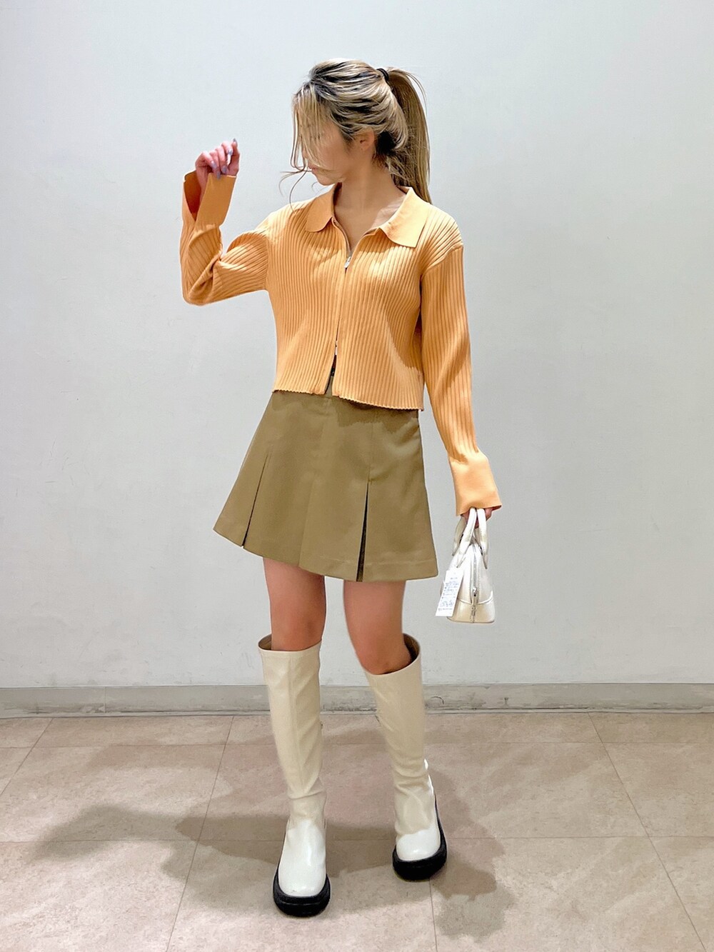 ベージュ系のニット/セーター、ホワイト系のショルダーバッグ、ベージュ系のスカートを着用したレディースの冬コーディネートの3枚目の写真