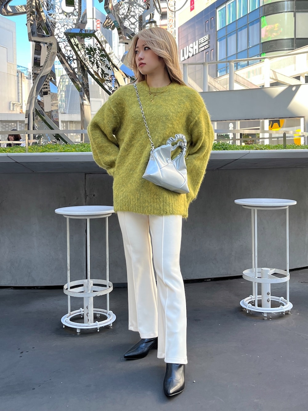 イエロー系のニット/セーター、シルバー系のショルダーバッグ、ホワイト系のスラックスを着用したレディースの秋コーディネートの2枚目の写真