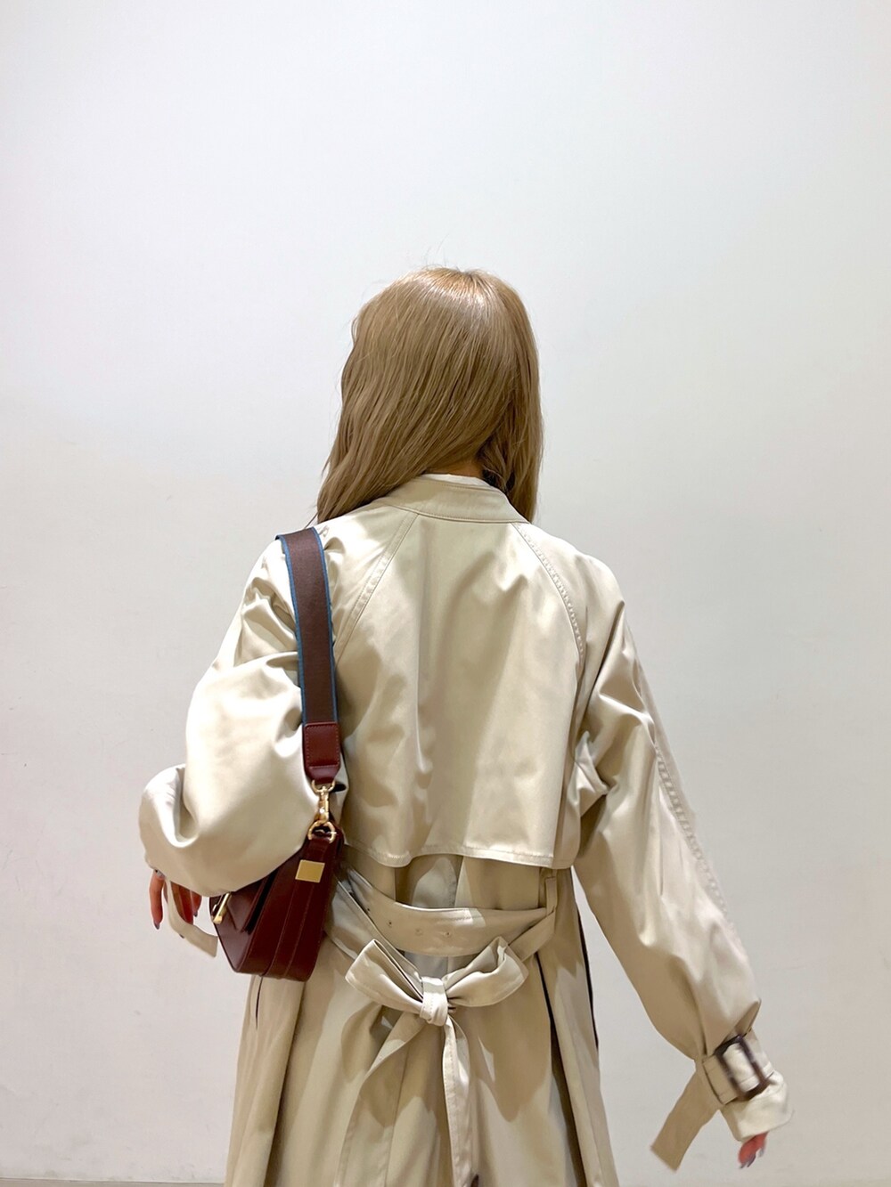 ホワイト系のシャツ/ブラウス、ベージュ系のトレンチコート、ブラウン系のショルダーバッグを着用したレディースの春コーディネートの6枚目の写真