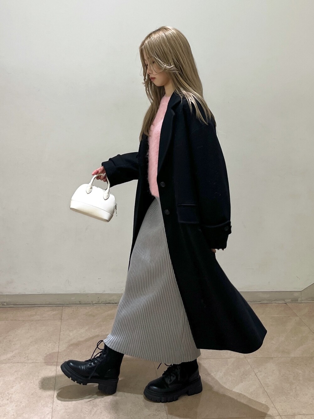 ピンク系のニット/セーター、ブラック系のチェスターコート、ブラック系のブーツを着用したレディースの冬コーディネートの8枚目の写真