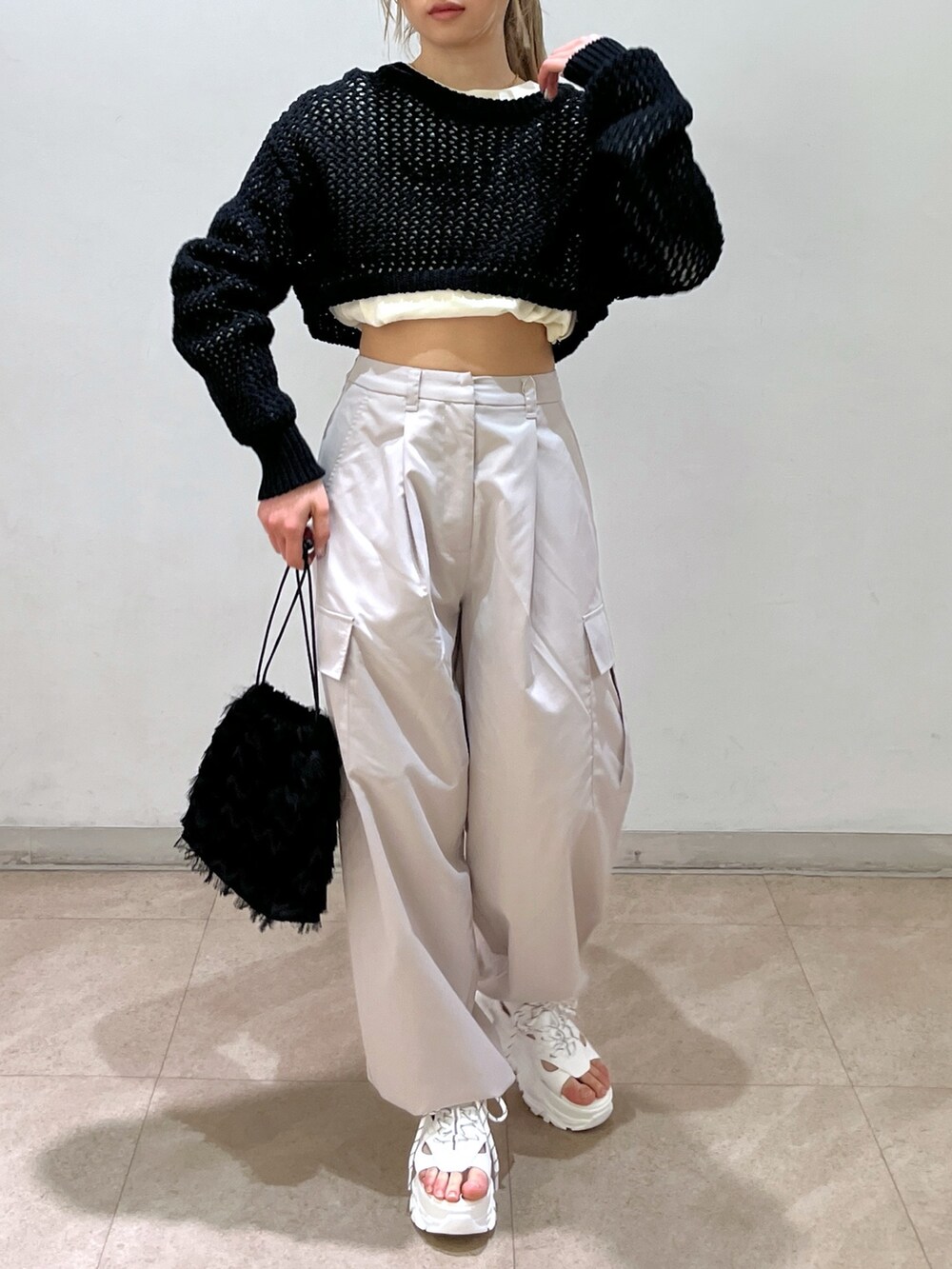 ベージュ系のカーゴパンツ、ブラック系のニット/セーター、ブラック系のハンドバッグを着用したレディースの春コーディネートの3枚目の写真