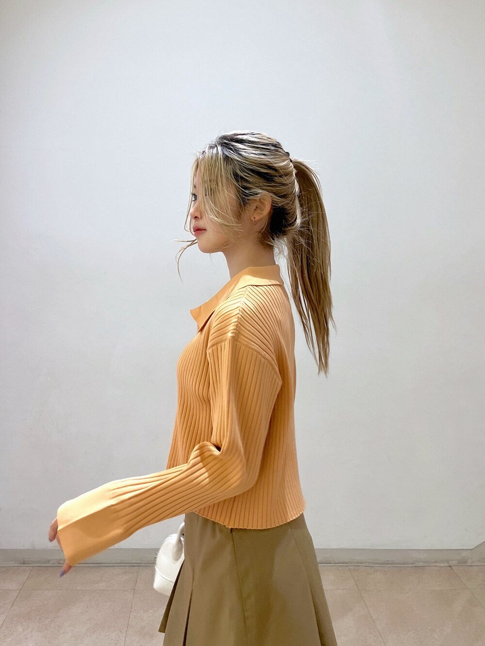 ベージュ系のニット/セーター、ホワイト系のショルダーバッグ、ベージュ系のスカートを着用したレディースの冬コーディネートの7枚目の写真