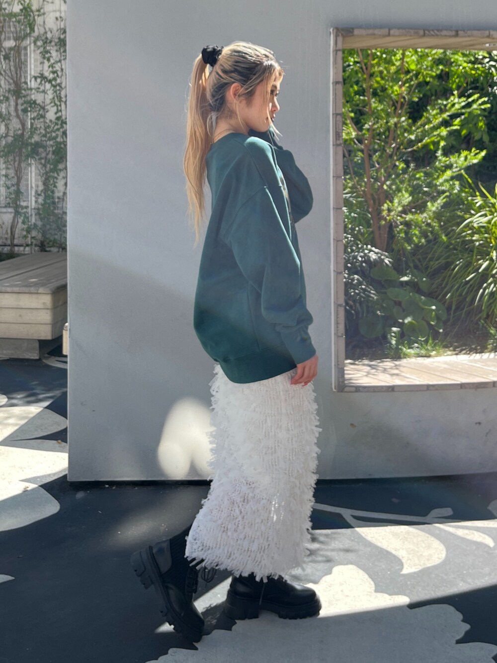 グリーン系のTシャツ/カットソー、ホワイト系のスカート、ブラック系のブーツを着用したレディースの秋コーディネートの5枚目の写真