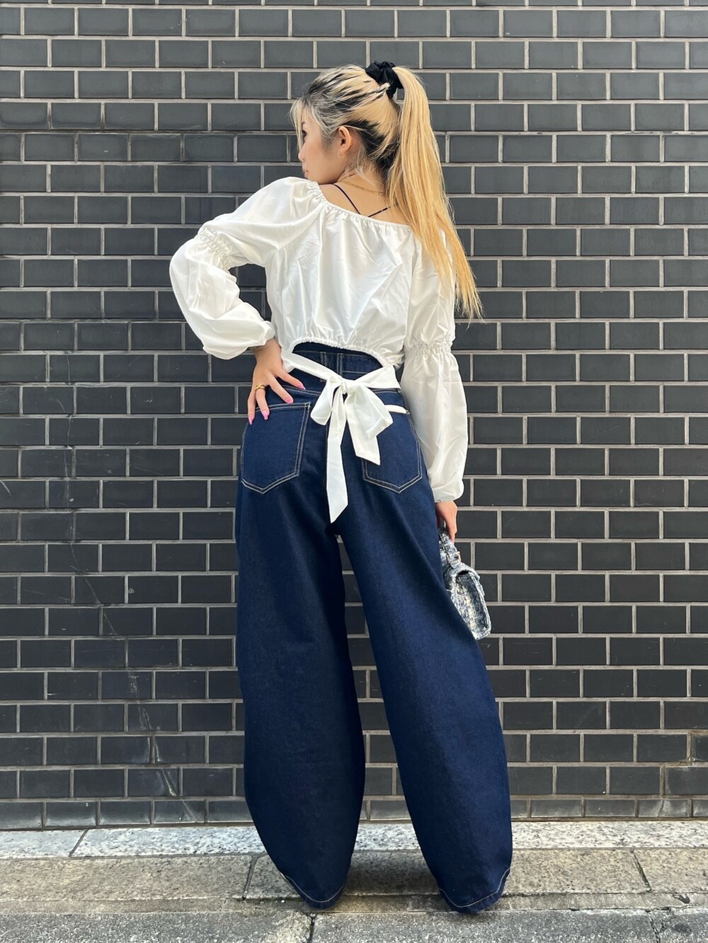 ブルー系のデニムパンツ、ホワイト系のシャツ/ブラウス、ブルー系のショルダーバッグを着用したレディースの秋コーディネートの2枚目の写真