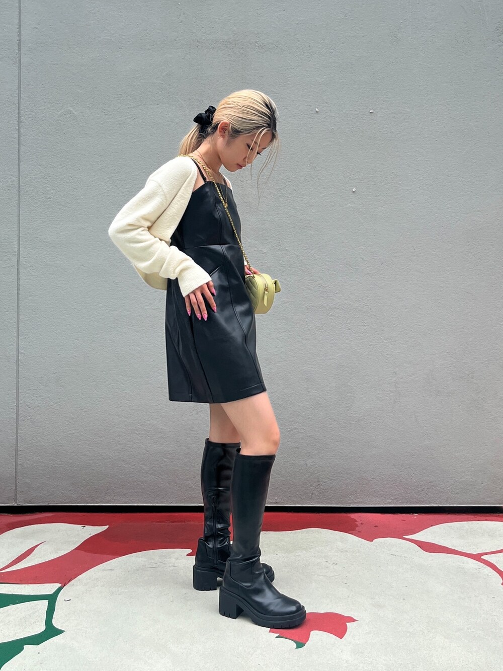 ブラック系のブーツ、ブラック系のワンピース、イエロー系のショルダーバッグを着用したレディースの秋コーディネートの2枚目の写真