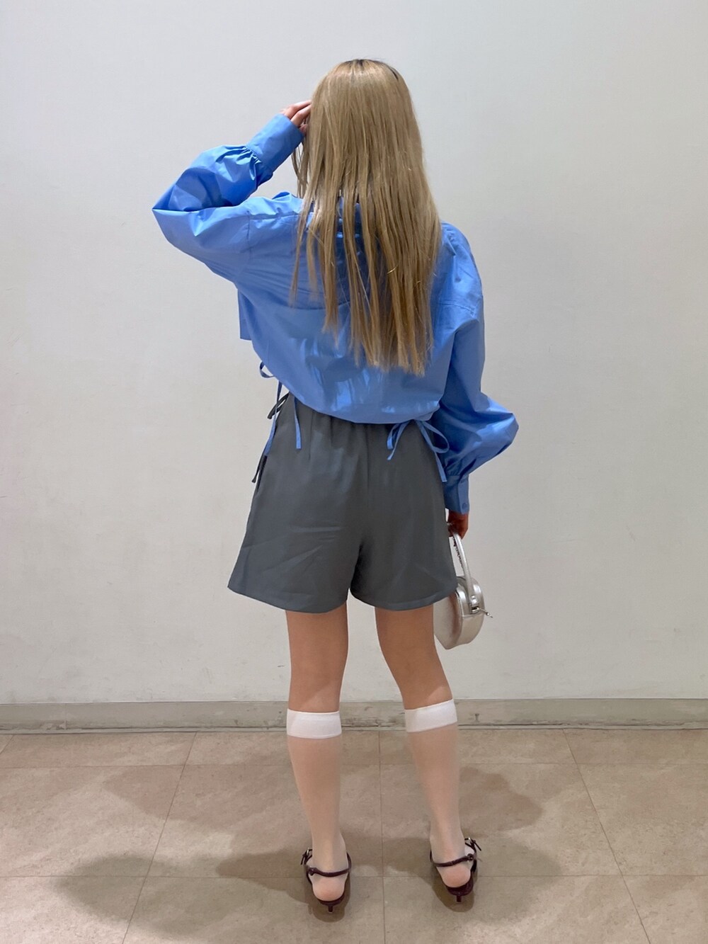 ブルー系のシャツ/ブラウス、グレー系のスカート、シルバー系のショルダーバッグを着用したレディースの春コーディネートの3枚目の写真