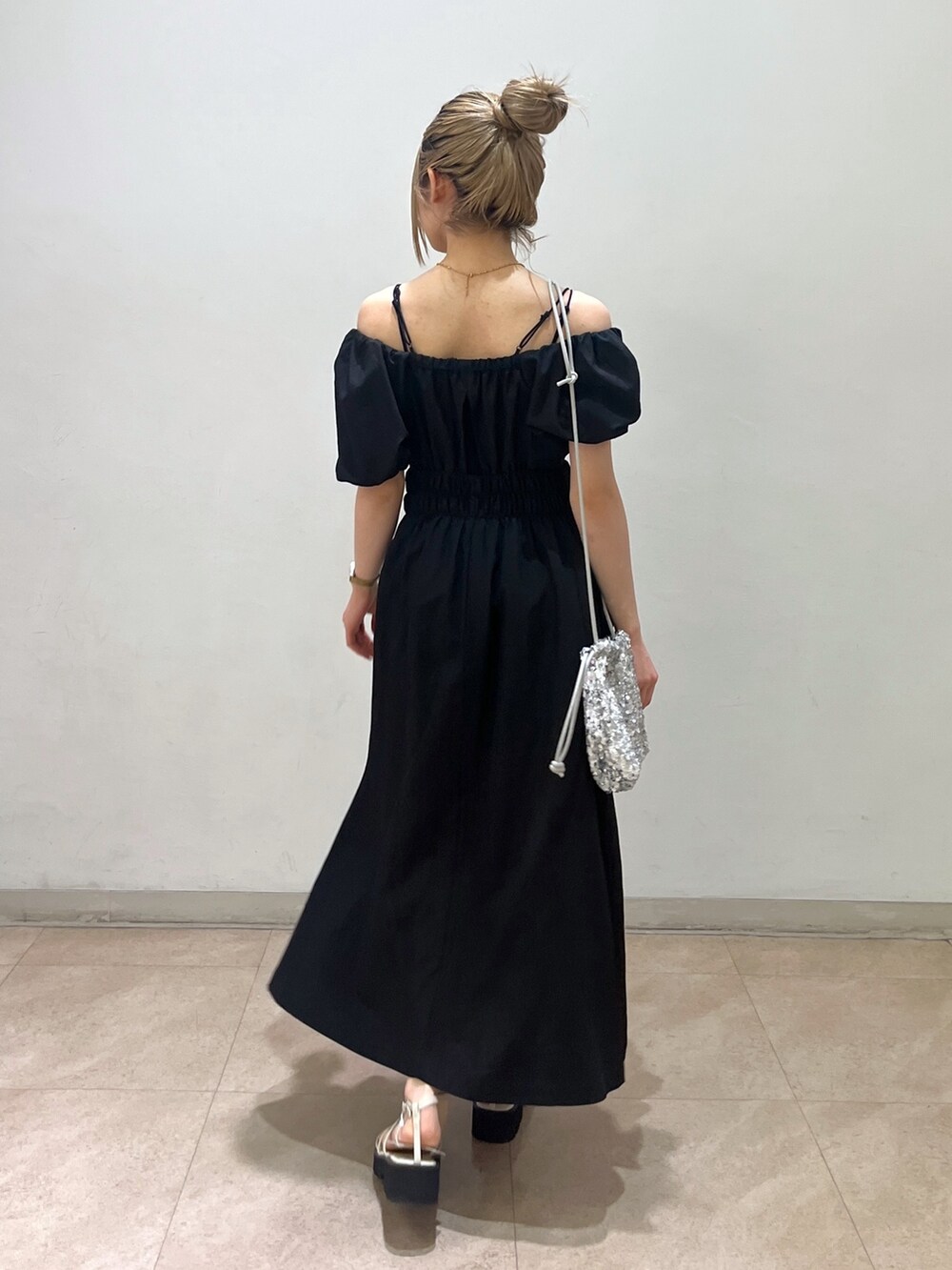 ブラック系のワンピース、シルバー系のハンドバッグ、ホワイト系のサンダルを着用したレディースの春コーディネートの4枚目の写真