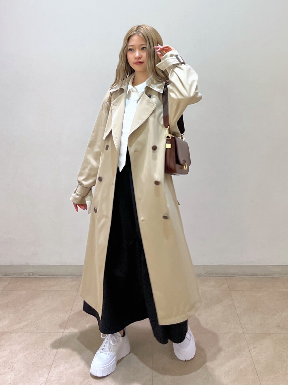 ホワイト系のシャツ/ブラウス、ベージュ系のトレンチコート、ブラウン系のショルダーバッグを着用したレディースの春コーディネートの2枚目の写真