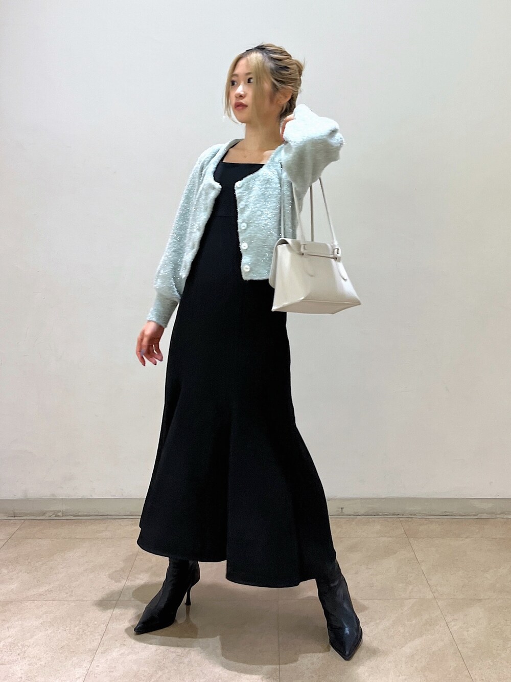 グリーン系のカーディガン/ボレロ、ホワイト系のショルダーバッグ、ブラック系のワンピースを着用したレディースの冬コーディネートの5枚目の写真