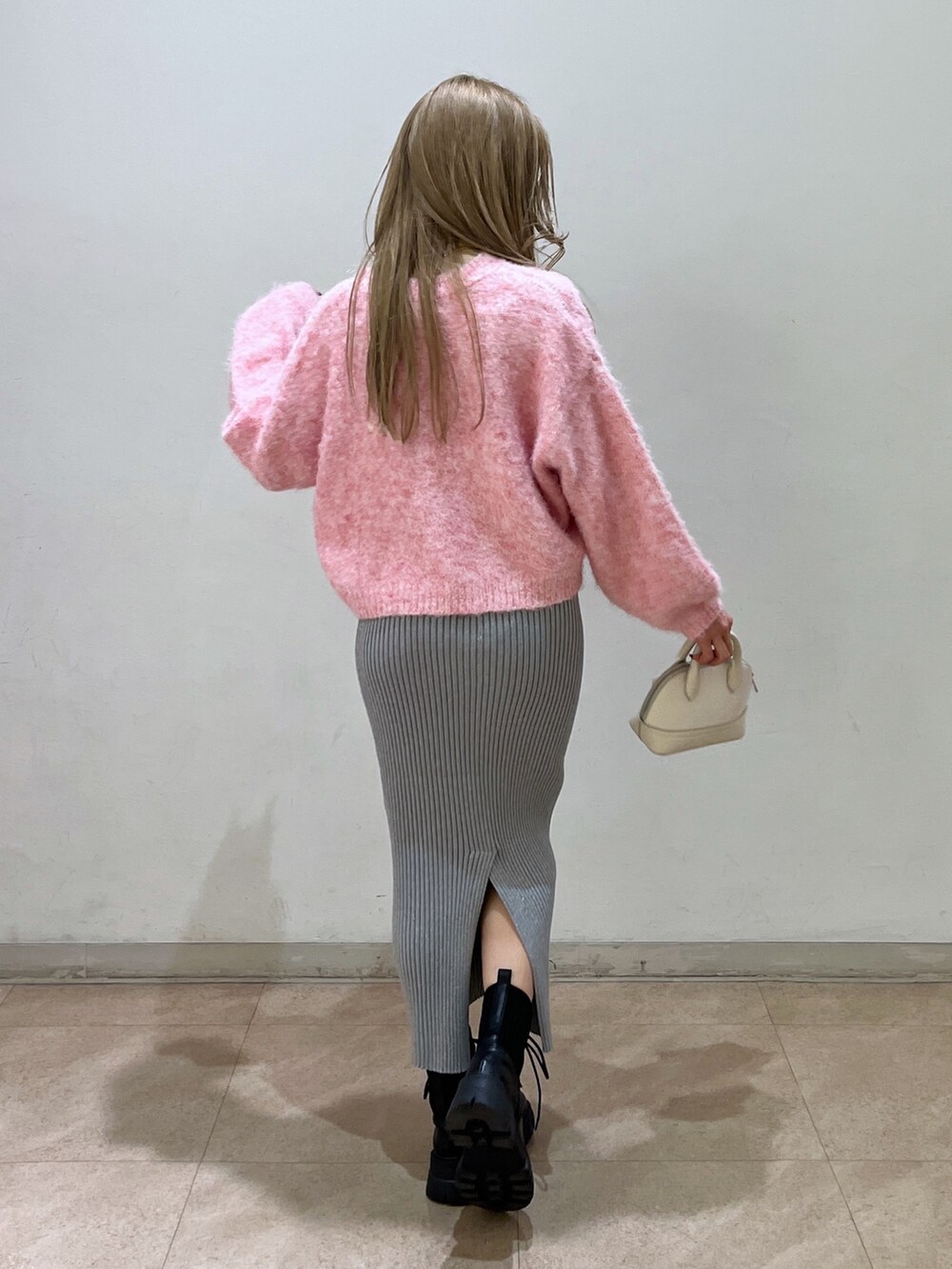 ピンク系のニット/セーター、ブラック系のブーツ、ホワイト系のショルダーバッグを着用したレディースの冬コーディネートの3枚目の写真