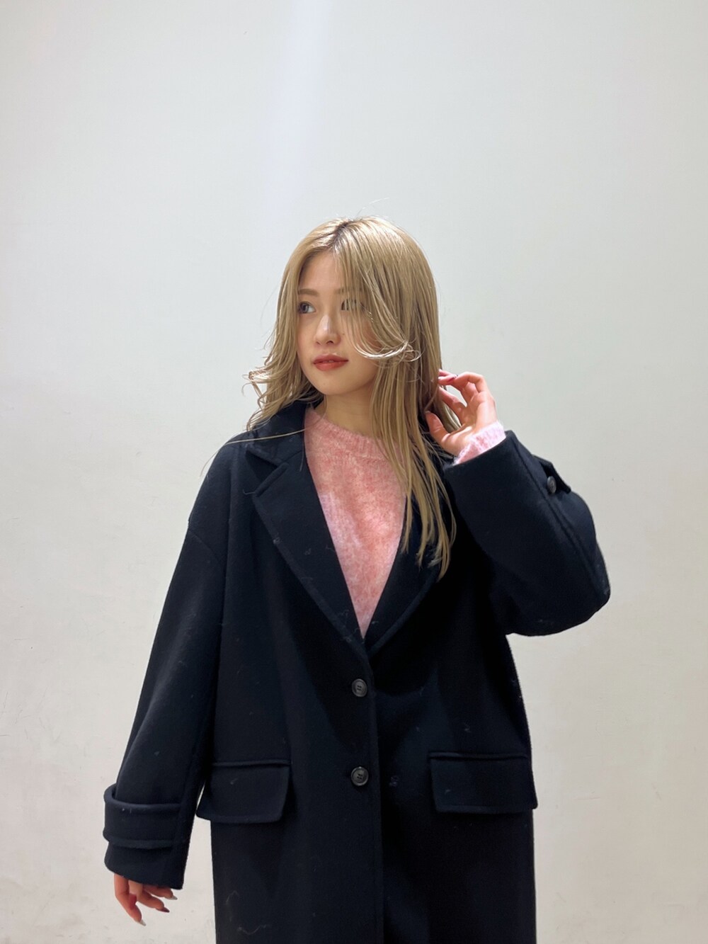 ピンク系のニット/セーター、ブラック系のチェスターコート、ブラック系のブーツを着用したレディースの冬コーディネートの9枚目の写真