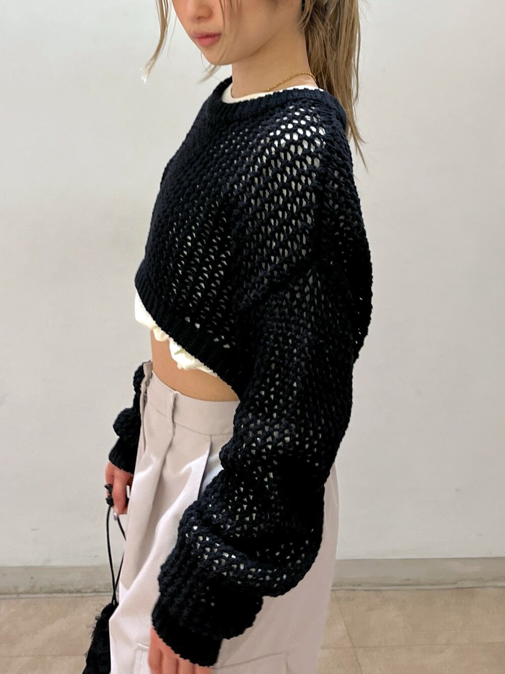 ベージュ系のカーゴパンツ、ブラック系のニット/セーター、ブラック系のハンドバッグを着用したレディースの春コーディネートの7枚目の写真