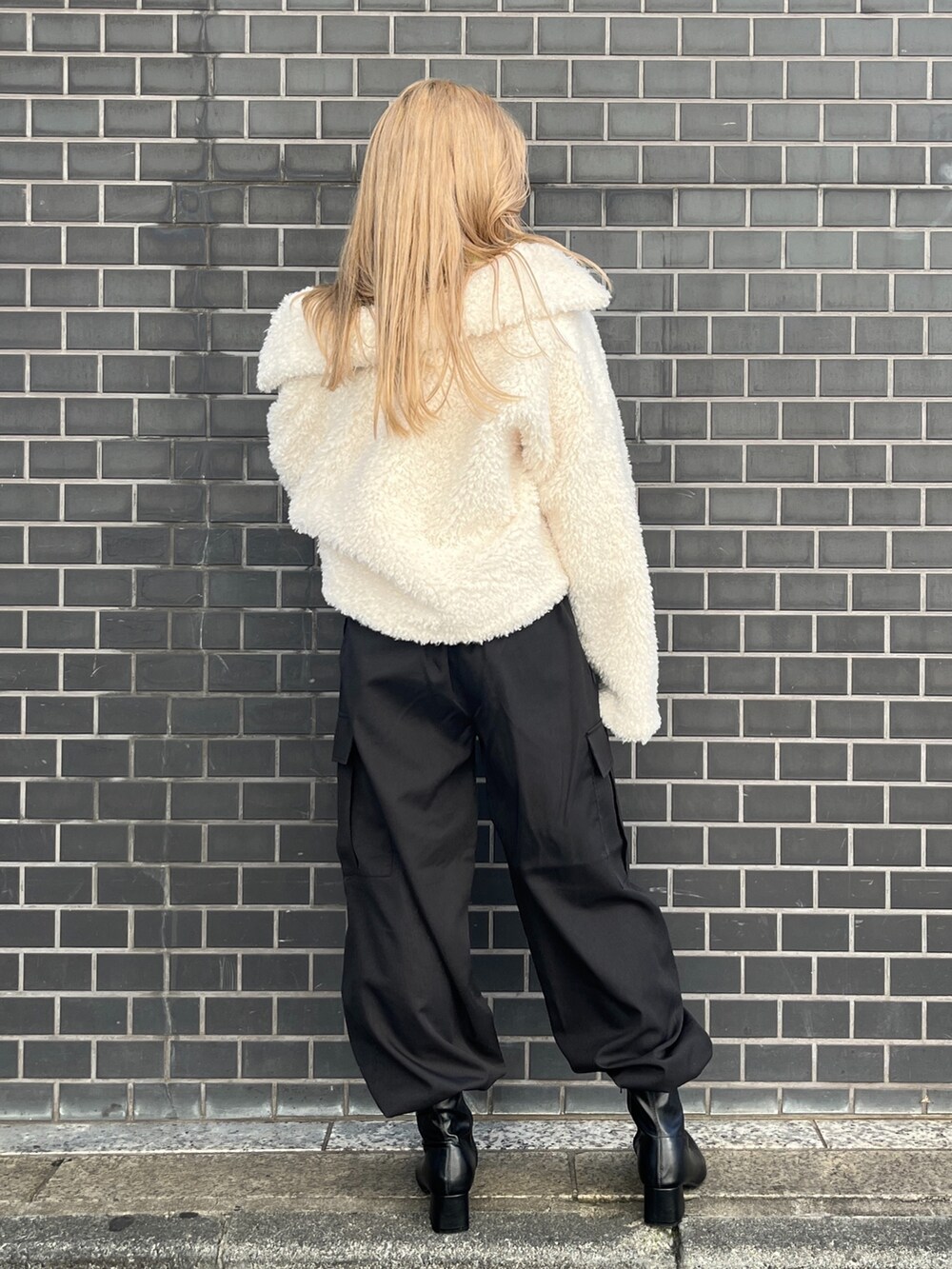 ホワイト系のブルゾン、ブラック系のカーゴパンツ、ブラック系のブーツを着用したレディースの秋コーディネートの3枚目の写真