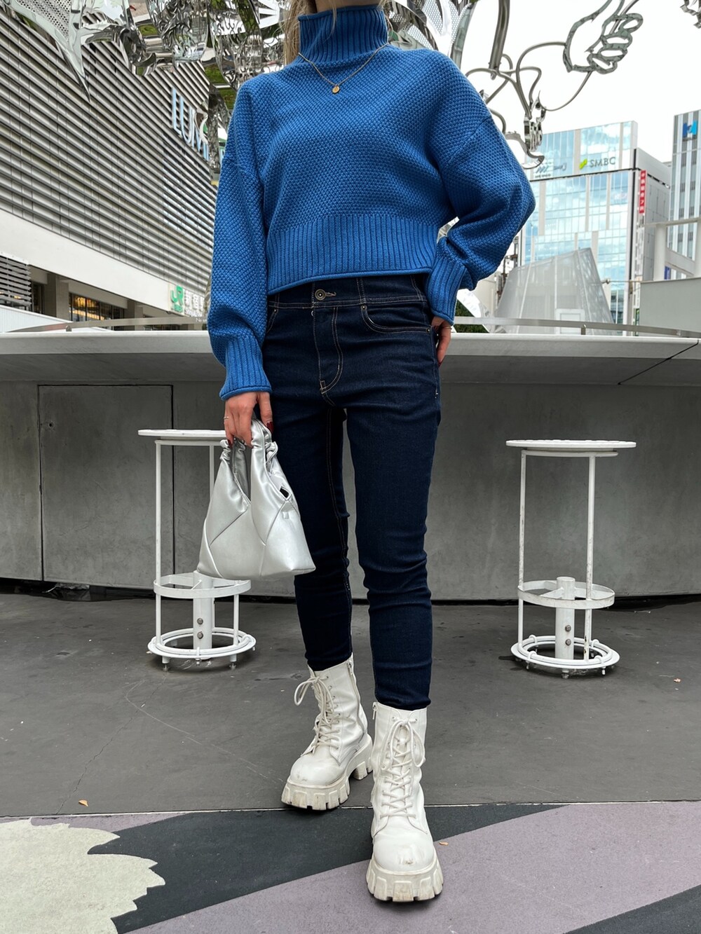 ブルー系のニット/セーター、ブルー系のデニムパンツ、シルバー系のショルダーバッグを着用したレディースの秋コーディネートの6枚目の写真