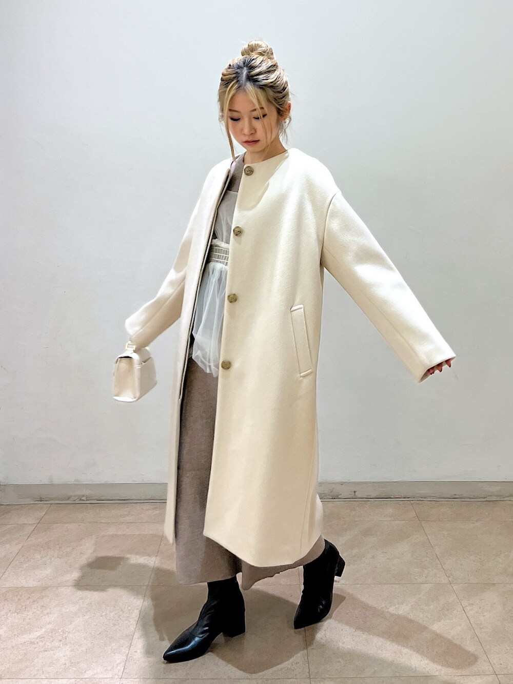 ベージュ系のノーカラーコート、ホワイト系のシャツ/ブラウス、ベージュ系のワンピースを着用したレディースの冬コーディネートの3枚目の写真