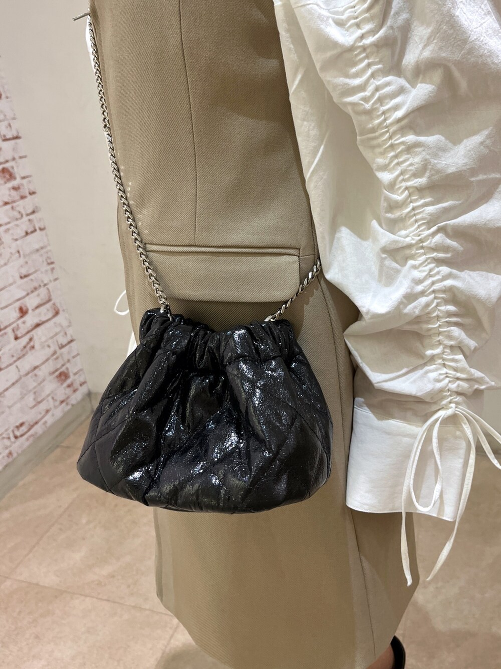 ブラック系のショルダーバッグ、ホワイト系のシャツ/ブラウス、ベージュ系のワンピースを着用したレディースの春コーディネートの9枚目の写真