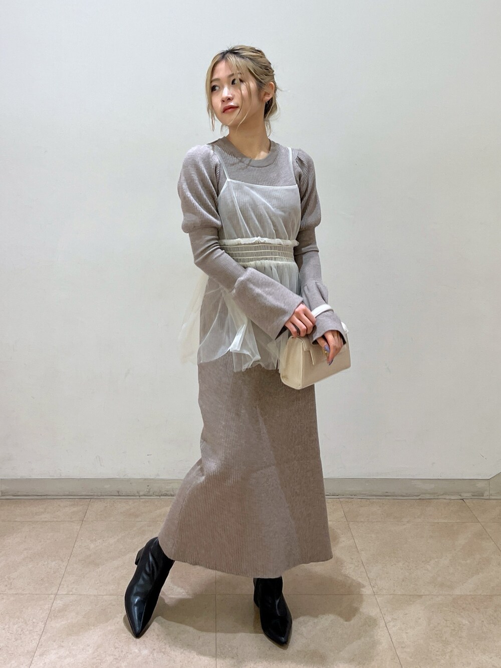 ホワイト系のショルダーバッグ、ブラック系のブーツ、ベージュ系のワンピースを着用したレディースの冬コーディネートの3枚目の写真