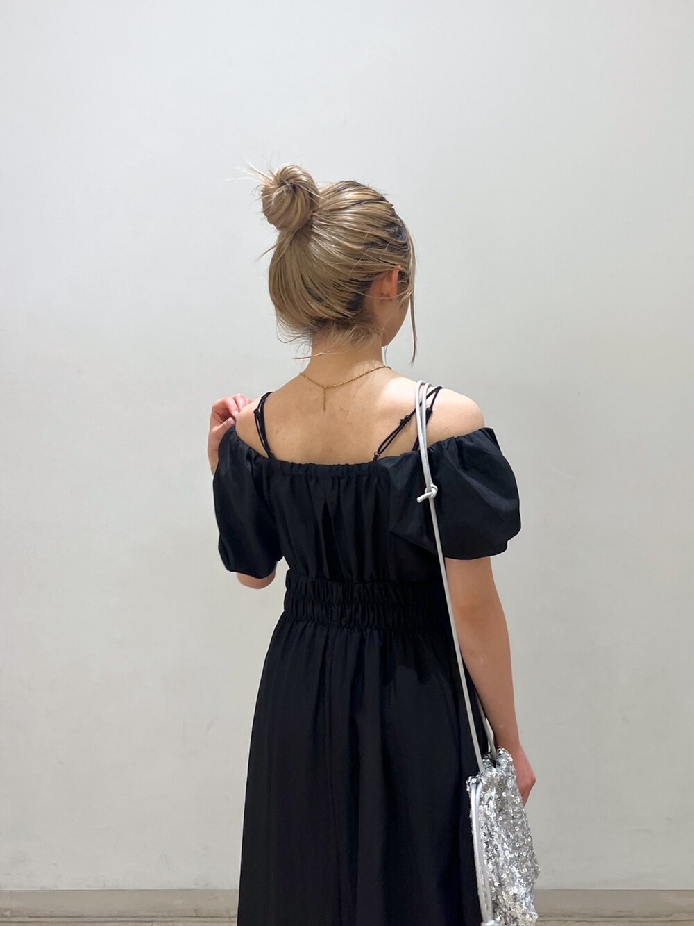 ブラック系のワンピース、シルバー系のハンドバッグ、ホワイト系のサンダルを着用したレディースの春コーディネートの6枚目の写真