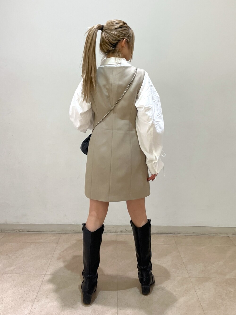 ブラック系のショルダーバッグ、ホワイト系のシャツ/ブラウス、ベージュ系のワンピースを着用したレディースの春コーディネートの3枚目の写真