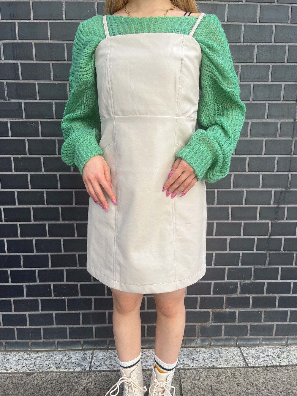 グリーン系のニット/セーター、ホワイト系のワンピース、ホワイト系のブーツを着用したレディースの秋コーディネートの7枚目の写真