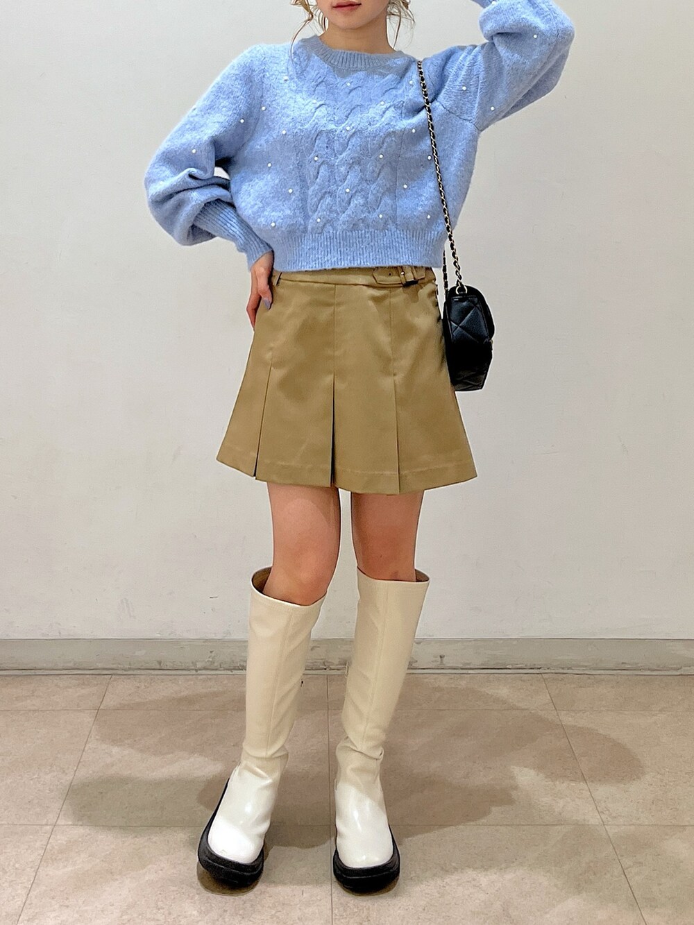 ブルー系のニット/セーター、ブラック系のショルダーバッグ、ベージュ系のスカートを着用したレディースの冬コーディネートの5枚目の写真