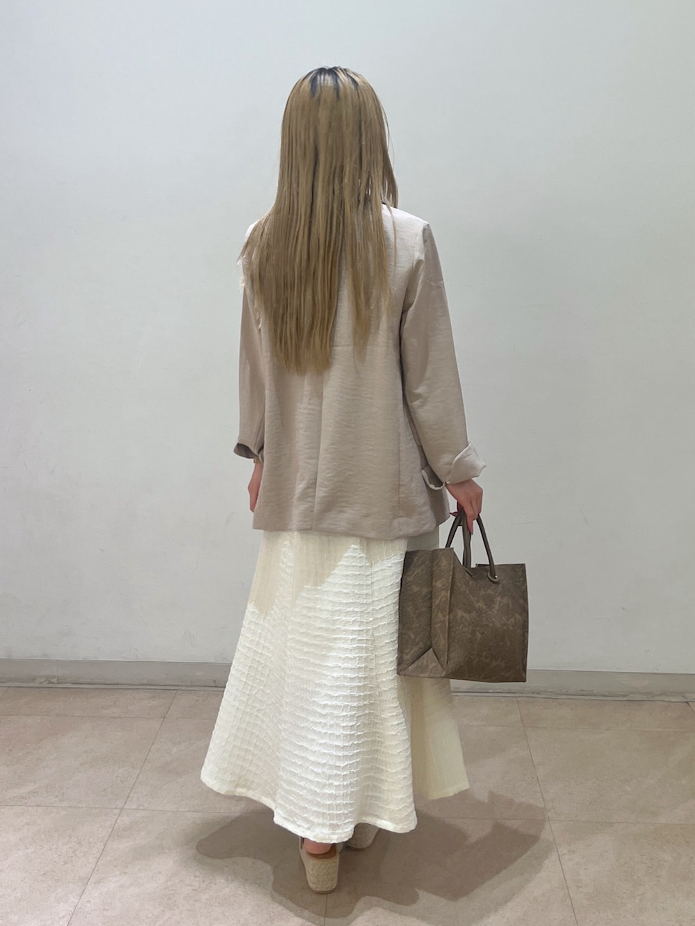 ベージュ系のテーラードジャケット、ブラウン系のショルダーバッグ、ホワイト系のワンピースを着用したレディースの春コーディネートの3枚目の写真