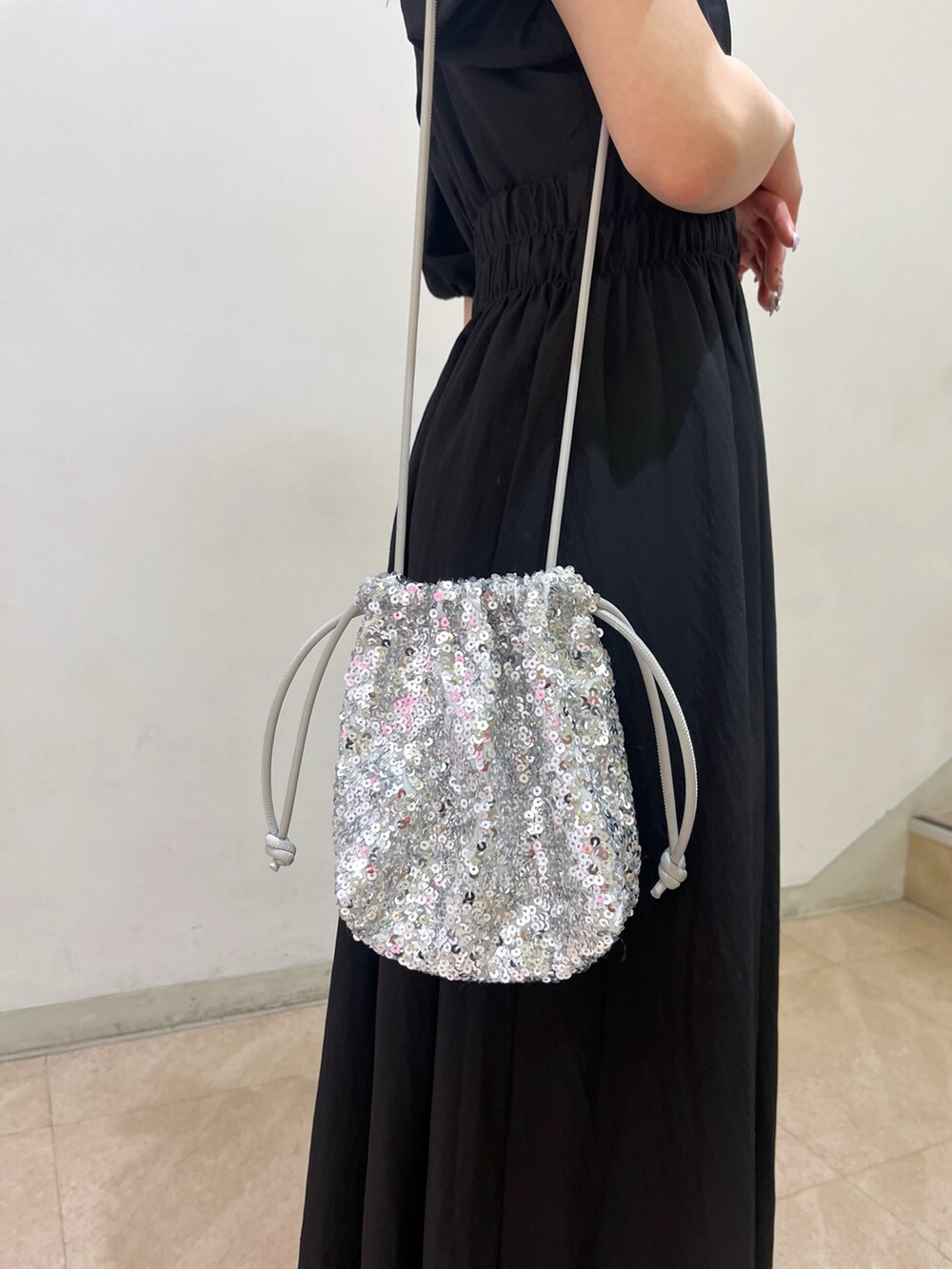 ブラック系のワンピース、シルバー系のハンドバッグ、ホワイト系のサンダルを着用したレディースの春コーディネートの10枚目の写真