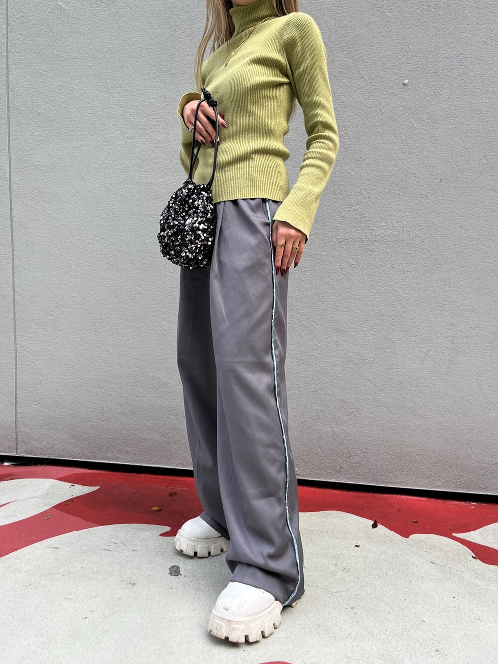 グリーン系のニット/セーター、グレー系のその他パンツ、ブラック系のハンドバッグを着用したレディースの秋コーディネートの6枚目の写真