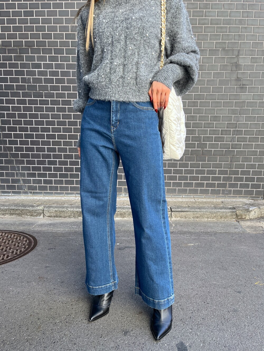 ブルー系のデニムパンツ、グレー系のニット/セーター、ホワイト系のトートバッグを着用したレディースの冬コーディネートの8枚目の写真