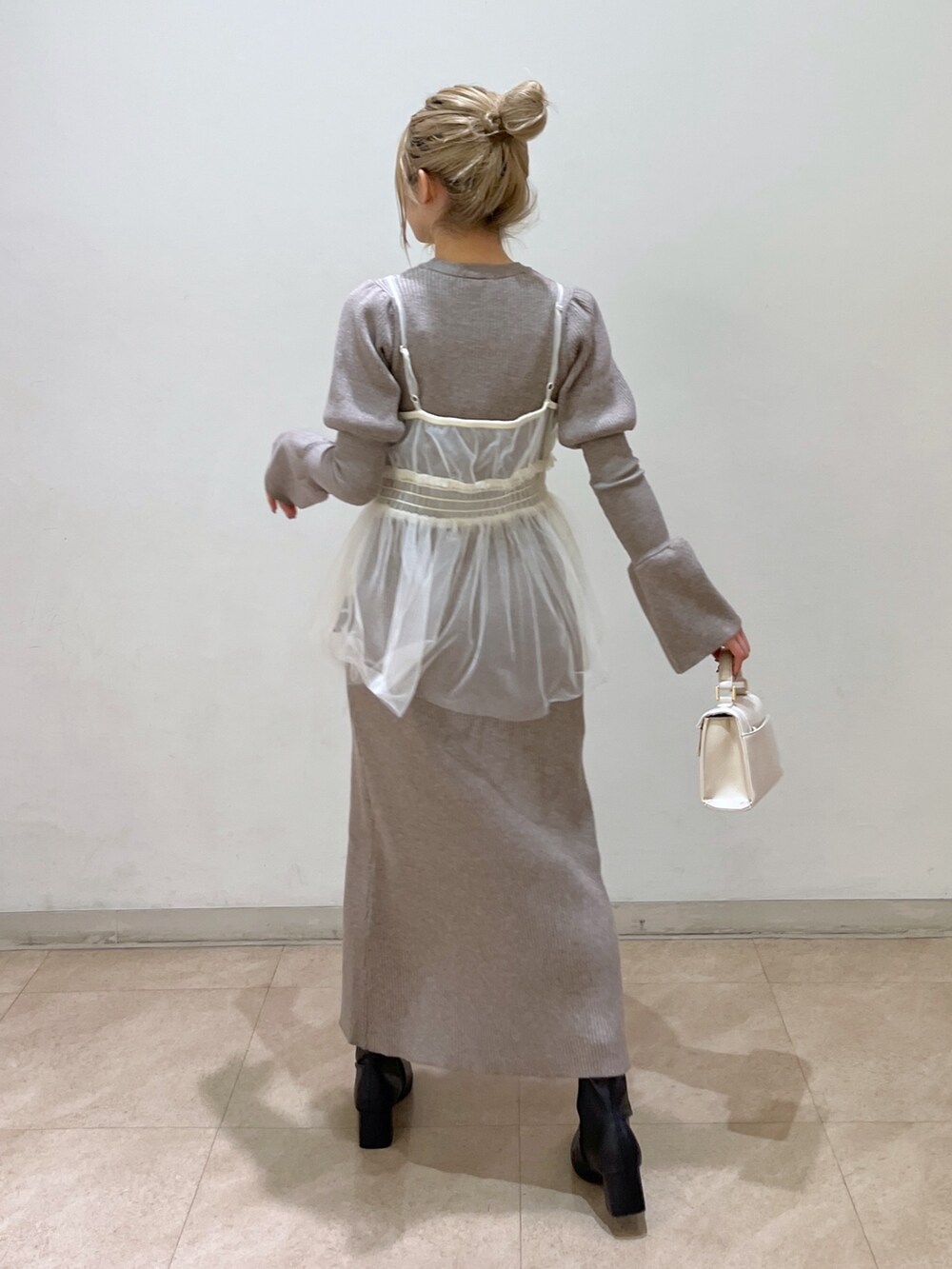 ホワイト系のショルダーバッグ、ブラック系のブーツ、ベージュ系のワンピースを着用したレディースの冬コーディネートの4枚目の写真