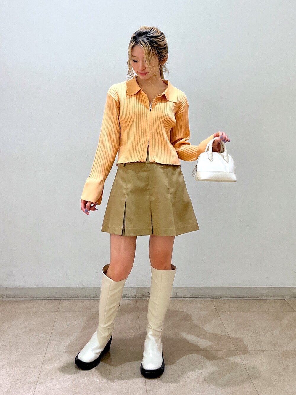 ベージュ系のニット/セーター、ホワイト系のショルダーバッグ、ベージュ系のスカートを着用したレディースの冬コーディネートの2枚目の写真