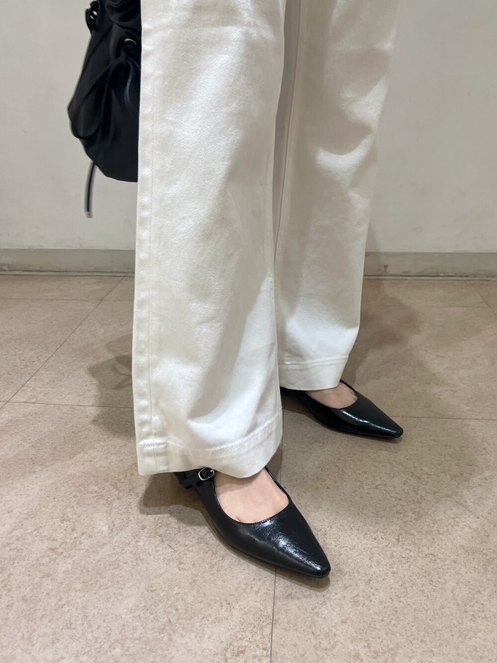 ホワイト系のデニムパンツ、ブラック系のショルダーバッグ、ブラック系のパンプスを着用したレディースの春コーディネートの10枚目の写真