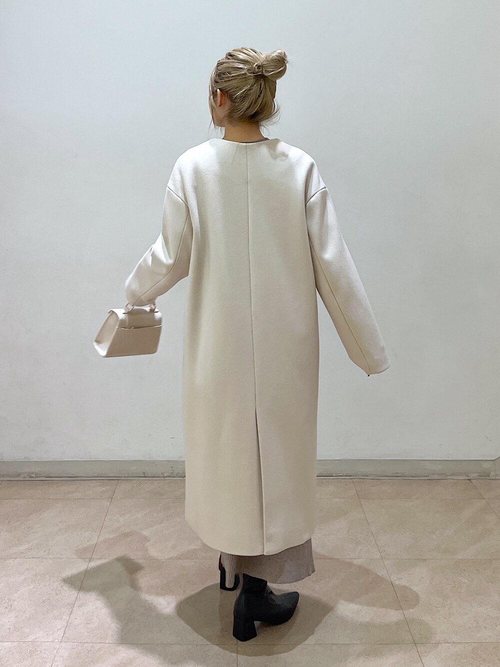 ベージュ系のノーカラーコート、ホワイト系のシャツ/ブラウス、ベージュ系のワンピースを着用したレディースの冬コーディネートの9枚目の写真