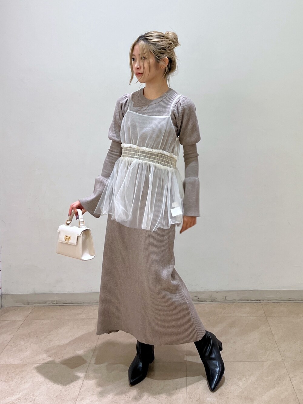 ホワイト系のショルダーバッグ、ブラック系のブーツ、ベージュ系のワンピースを着用したレディースの冬コーディネートの2枚目の写真