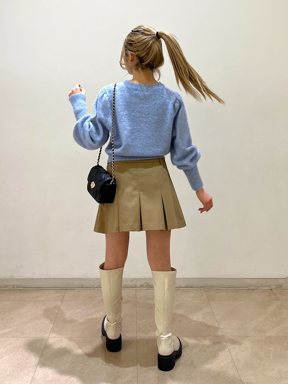 ブルー系のニット/セーター、ブラック系のショルダーバッグ、ベージュ系のスカートを着用したレディースの冬コーディネートの4枚目の写真
